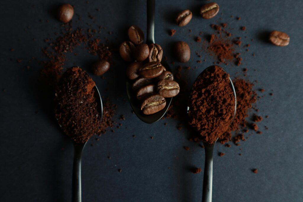 coffee beans and ground coffee, balanced on spoons